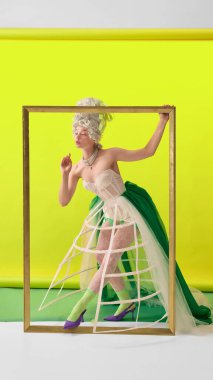 Korseli zarif rokoko kadın sarı arka planda altın çerçeveden geçiyor. Lüks parfüm hikaye anlatımı, moda kampanyası ve modern yaşam tarzı markalaşması kavramı.