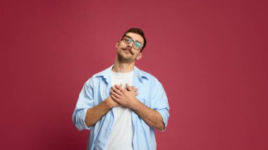 Minnettar bir adam göğsünde el ele tutuşup nezaket ve duygusal samimiyet gösteriyor. Empati, minnettarlık, zihinsel sağlık bilinci, medyada ve eğitimde duygusal zeka kavramı.