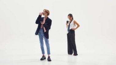 İki stil sahibi profesyonel, yaratıcı aralarda kahve içip telefonları kontrol ediyorlar. Modern başlangıç kültürü için dijital yaşam tarzı, rahatlama ve işyeri dengesi kavramı.