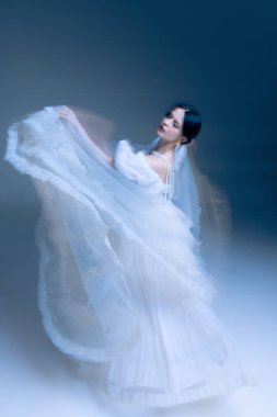 Uzun inci iplikleri, yumuşak mavi ambiyansı ve hareket bulanıklığı olan fırıl fırıl dönen geceliğin arka görünüşü. Mücevher kimliği kavramı, iç dekorasyon stili ve hareketin farkındalığı.