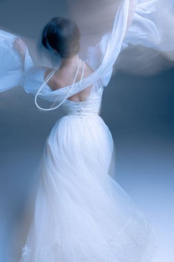 Beyaz elbise ve inciler hafif bulanık, kollar göksel ışıkta yükseliyor. Modern dans yoluyla moda aksesuarları, iç denge ve duygusal ifade kavramı.