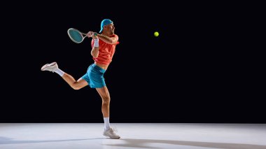 Odaklanmış tenis oyuncusu kontrollü hareket ve enerjiyle topa vuruyor. Yaşam tarzı fotoğrafçılığı, pozitiflik, hareket özgürlüğü, insan ifadesi ve yaratıcı tasarım tasarımı.