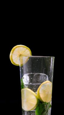 Siyah arka planda köpüklü içeceğe düşen limon dilimini yakınlaştır. Tazelik, vitamin yaşam tarzı, içecek markaları, yaz görselleri ve ürün tasarımı konsepti.
