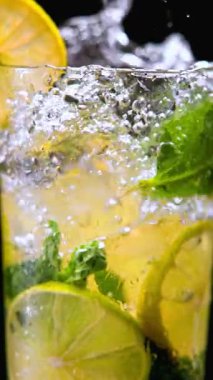 İçkinin bardağa limon ve naneli şekerlemeyle dolup taşması. Tazelik, lezzet, içecek markalaşması, reklamcılık ve refah tasarımı için sağlık yaşam tarzı kavramı.