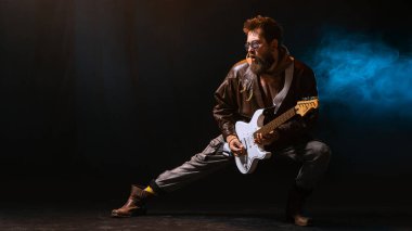 Elektro gitarist duygusal ifadeyle mavi dumanda solo çalıyor. Müzik akışı kavramı görsel, kendini ifade etme, motivasyon ve tutkulu sanatçılar için yaratıcı reklam..