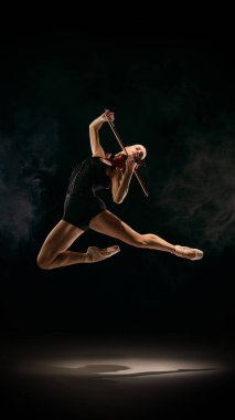 Balerin kemanla zıplıyor dinamik sahne füzyonu yaratıyor. Dans-müzik melezi kavramı, tiyatro tanıtımı, sanat eğitimi materyalleri, kültür projeleri için dışavurumcu hareket.