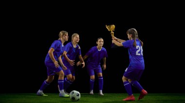 Genç futbolcu maç sonrası takım arkadaşlarına kupa sunuyor. Gençlik sporları seremonisi, ödül etkileşimi, takım kültürü, başarı promosyonu.