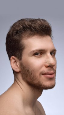 İyileşme sürecinde burun bandajıyla hafifçe gülümseyen bir adam. Ameliyat sonrası iletişim, klinik pazarlama, iyileşme aşaması belgeleri ve hasta bakımı görselleri kavramı.