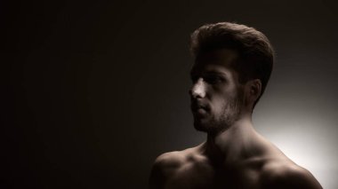 Dar dramatik ışınla aydınlatılmış burun bandajlı bir adamın sade yan portresi. Estetik cerrahi iyileşme, duygusal hikaye anlatma ve sağlık hizmetleri iletişimi için görsel anlatılar kavramı.