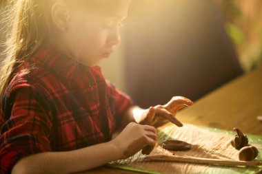 Sıcak güneş ışığında kil heykel yapan bir kız. Çocukluk yaratıcılığı, odaklanmış öğrenme, pratik eğitim, sanatsal zanaat becerileri ve hassas duygusal bağlılık kavramı.