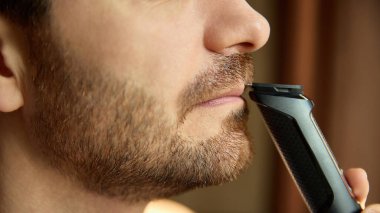Elektrikli traş makinesi kullanarak bıyık kesme. Bakım malzemeleri, erkek blogları, tıraş aleti markalaşması, doğru detaylandırma, temiz bakım görselleri kavramı.