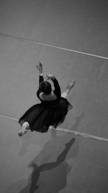 Sahne eğitimi sırasında atlama egzersizi yapan siyah ve beyaz balerin. Düzenli aşama çalışmaları için aralık değerlendirmesi, teknik arıtma ve kontrollü hareket testi kavramı.