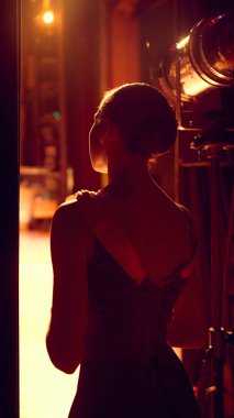 Sahne kenarına konumlanmış bir balerin sahne ışıklarına bakıyor. İşaret hazırlığı kavramı, icracı hazırlık durumu ve giriş öncesi gerilim dizilimi aşama iş akışı içinde.