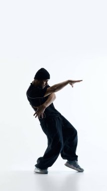 Şehir dansçısı beyaz arka planda stüdyoda etkileyici kol hareketleri yapıyor. Modern görsel projeler için yaratıcı kendini ifade kavramı, çağdaş dans kültürü, özgürlük ve odaklanmış enerji kavramı.