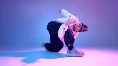 Çağdaş dansçı neon renkli stüdyoda yer hareketleri sergiliyor. Dans eğitimi tanıtımı, yaratıcı eğitim görselleri ve modern performans pazarlaması kavramı.