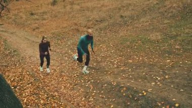 Athletic couple trail running uphill in autumn forest. Concept of outdoor fitness motivation, endurance training, active lifestyle content for sports brands and wellness campaigns.