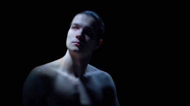 Sinematik düşük ışıkta yansıtıcı ifadeli bir erkek portresi. Duygusal farkındalık kampanyaları, zihinsel refah görselleri, estetik klinik iletişimi ve premium marka hikaye anlatımı kavramı.