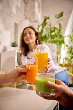 İçi sıcacık, taze meyve sularıyla dolu bardakları tıkırdatan eller. Kutlama anlayışı, sağlıklı yaşam tarzı, taze malzemeler, dostane atmosfer ve doğal içeceklerin ortak zevki..