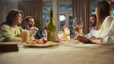 Şarap şişesi ve bardaklar, arka planda oturan ve konuşan arkadaşlarla birlikte yemek masasına yerleştirildi. Ürün reklamları, restoran görselleri, içecek markalaşması, menü tasarımı ve tanıtım içeriği kavramı.