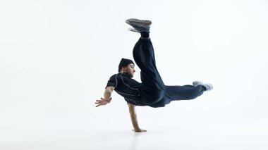 Sokak dansçısı beyaz stüdyoda hareketli break dans gösterisi yapıyor. Özgürlük kavramı, hareket akışı, şehir kültürü ve anlamlı modern dans yaşam tarzı..