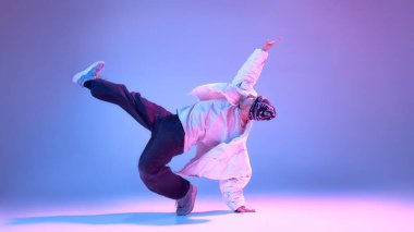 Erkek hip hop dansçısı stüdyoda bacağını uzatarak dengede duruyor. İleri dans tekniği, dayanıklılık eğitimi, şehir koreografisi, fiziksel kontrol ve yaratıcı disiplin kavramı..