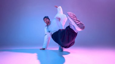 Erkek dansçı stüdyoda bacaklarını uzatarak denge hareketi yapıyor. Güç ve esneklik eğitimi, ileri koreografi, şehir dans eğitimi ve fiziksel disiplin kavramı.