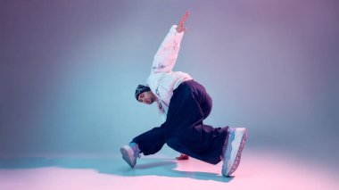 Breakdance dansçısının sahne dengesi stüdyoda hafif arka planda hareket ediyor. Sokak dansı eğitimi, vücut kontrolü, esneklik, modern koreografi ve gençlik kültürü kavramı.