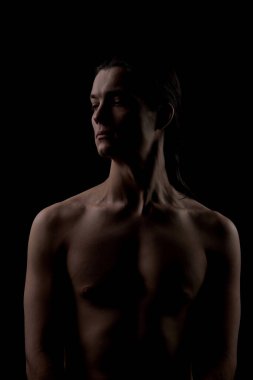 Deri dokusunu vurgulayan yan ışıklandırmalı sade bir erkek portresi. Cilt farkındalığı, vücut güveni, kendini kabullenme, asgari estetik ve otantik erkek güzelliği kavramı..