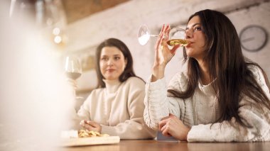 Evde rahat bir yaşam tarzında beyaz şaraptan hoşlanan bir kadın. Yaşam tarzı içecek reklamları, şarap markalaşması, sosyal medya alkol tanıtımı, günlük ev tüketimi ve modern yetişkin eğlencesi kavramı.