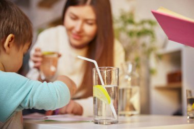 Aile rutini sırasında bir bardak limonlu su. Günlük hidrasyon, temiz içecek seçimi, evdeki sağlıklı yaşam tarzı, dikkatli tüketim ve dengeli aile alışkanlıkları kavramı.