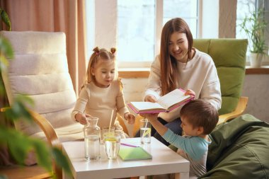 Anne ve çocuklar evde birlikte eğitici zaman geçiriyorlar. Pozitif ebeveynlik, erken öğrenim ortamı, aile yaşam tarzı, duygusal bağlantı ve sağlıklı çocukluk gelişimi kavramı.