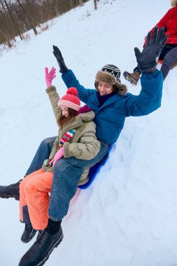 Genç çift karlı tepede kızak kayıyor. Kışın açık hava aktivitesi, çiftler için mevsimsel eğlence, günlük boş zaman, soğuk hava eğlencesi ve kış seferleri için yaşam tarzı içeriği kavramı.