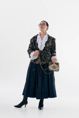 Çiçekli ceketli zarif bir kadın stüdyo resmi ve kendine güveni tam. Kalıtım modası, romantik dokular, entellektüel kadınlık, retro esinlenilmiş yazı işleri ve yaşam tarzı estetiği kavramı.