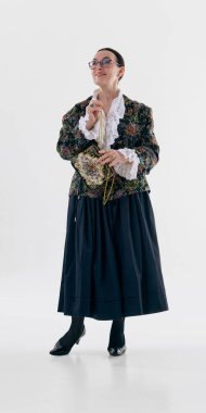 Çiçekli ceketli ve fırfırlı bluzlu bir kadın, kendine güveni tam klasik bir çanta tutuyor. Romantik moda kavramı, klasik detaylar, kadınsı zarafet ve editoryal kıyafet estetiği..