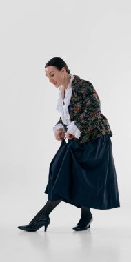 Çiçekli ceketli olgun bir kadın zarif yüksek topuklu ayakkabı giyiyor. Ayakkabı sunumu, moda ayrıntıları, klasik tarz, ayakkabı reklamcılığı, yaşam tarzı ve editoryal kullanım kavramı.