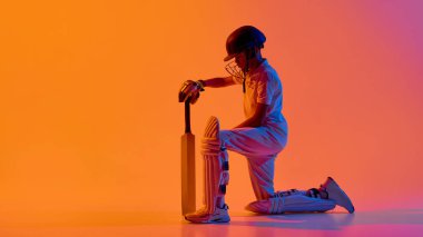 Kriket oyuncusu elinde sopayla mor arkaplanı tutuyor. Çağdaş spor pazarlama, gençlik kriket akademisi tanıtımı, dinamik eğitim görselleri ve yaratıcı tasarım kavramı.