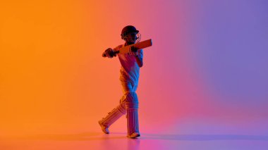 Genç kriket oyuncusu stüdyo gradyan ışığında savunma atışı yapıyor. Kriket koçluğu içeriği, teknik eğitim rehberleri, spor dergisi düzeni ve genç atletizm markaları kavramı.