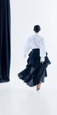 Beyaz arka planda dalgalı siyah etekli bir kadın yürüyor. Podyum fikri kampanya görselleri, mevsimsel koleksiyon tanıtımı, moda markası tanıtımı ve yaşam tarzı reklamları..