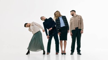 Beyaz stüdyo arka planında eşgüdümlü bir şekilde yan yana duran dört yetişkinden oluşan bir grup. Takım çalışması dengesi, ortak yön, işbirliği ve modern topluluk dinamiği kavramı.