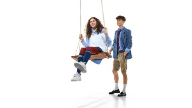 Genç kız, beyaz ceketli bir oğlanla okul kıyafeti içinde sallanıyor. Okul üniforması modası, gençlik stili sunumu ve ticari giyim markası kavramı.