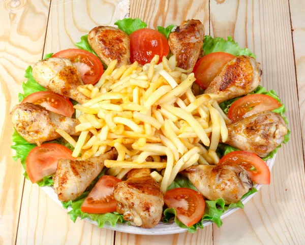 kızarmış tavuk budu, patates ve sebze ahşap bir masa üzerinde