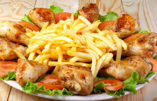 kızarmış tavuk budu, patates ve sebze ahşap bir masa üzerinde