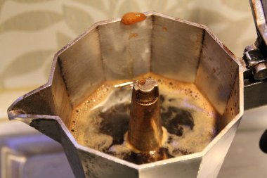 Kahve yapmak için metal bir moka, çaydanlık, makineden çıkan kaynar kahve.