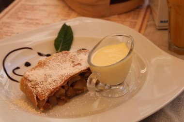 Beyaz tabakta vanilya soslu elmalı turta.