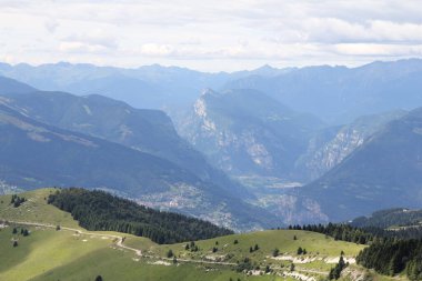 Dağların ve vadilerin manzarası, yeşil, bitki örtüsü ve tepeler arasındaki yol, mavi gökyüzü ve bulutlar
