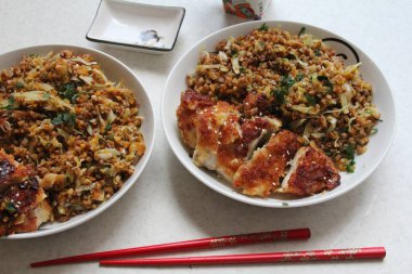 Karabuğday dolu tabaklar sebzeli ve ekmek kırıntılı tavuk dilimlenmiş Asya usulü mutfak, yemek çubukları.