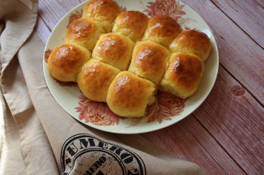 Ev yapımı maya çörekleri, brioche çörekleri, parlayan çörekler, bir tabakta ev yapımı pişmiş yiyecekler.