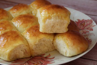 Ev yapımı maya çörekleri, brioche çörekleri, parlayan çörekler, bir tabakta ev yapımı pişmiş yiyecekler.