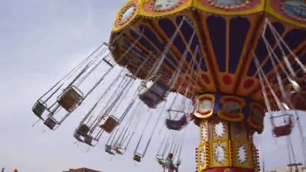 Kedjans karusell snurrar i nöjesparken. flickor rida swing på helgen — Stockvideo