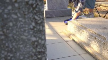 Mezarlığı temizliyorum. Bir kadın mezarda gri anıtı paçavrayla yıkıyor..